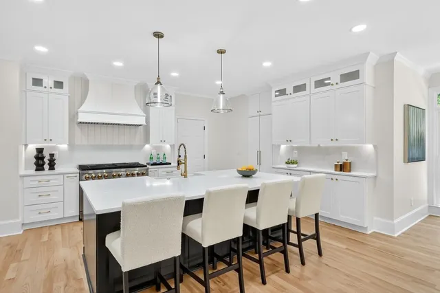 a kitchen with stainless steel appliances a table chairs stove and white cabinets