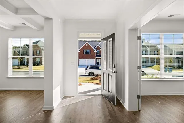 a view of an empty room with wooden floor and a window