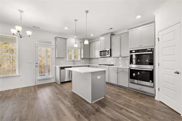 a large white kitchen with kitchen island a sink a stove a refrigerator and a stove with wooden floor