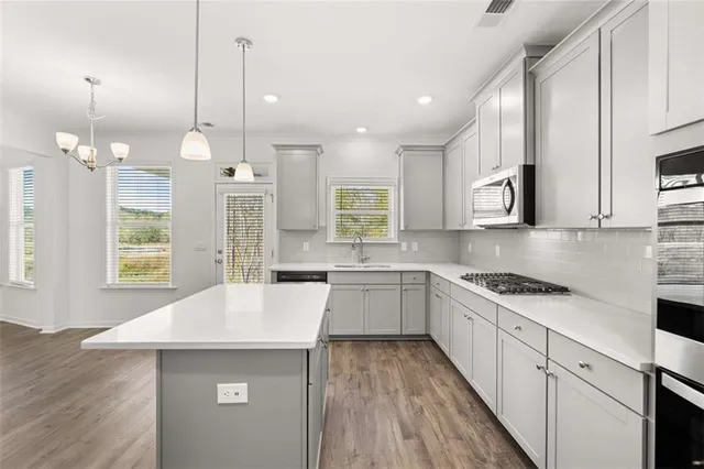 a large kitchen with kitchen island a large island in the center and stainless steel appliances