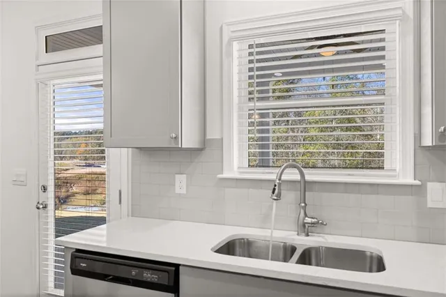 a view of an empty room with wooden floor and a kitchen
