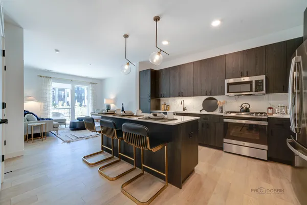 a kitchen with kitchen island granite countertop stainless steel appliances a sink a stove a refrigerator cabinets and wooden floor
