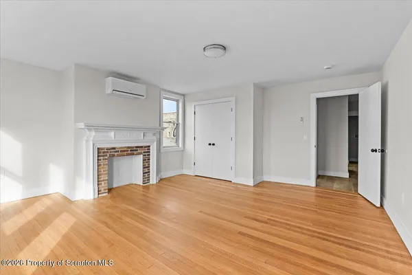 a view of empty room with wooden floor and fireplace