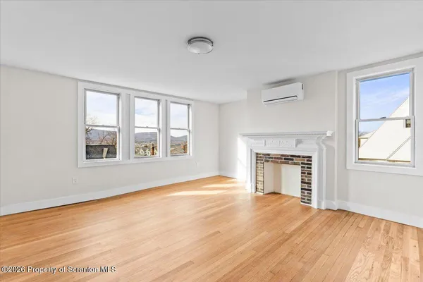 a view of an empty room with window and wooden floor