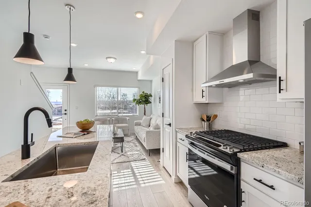 a kitchen with stainless steel appliances granite countertop a stove a sink a refrigerator and a wooden floors