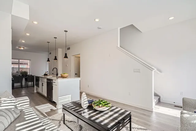 a kitchen with stainless steel appliances kitchen island granite countertop a refrigerator oven a sink dishwasher and white cabinets with wooden floor