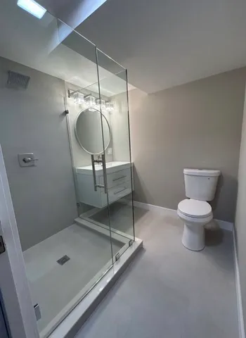 a bathroom with a granite countertop toilet a sink and a mirror