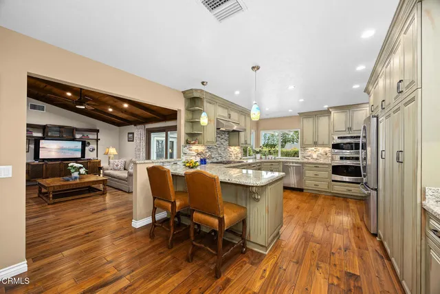 a dining hall with stainless steel appliances granite countertop a stove and a refrigerator