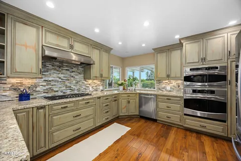 a kitchen with granite countertop white cabinets and stainless steel appliances