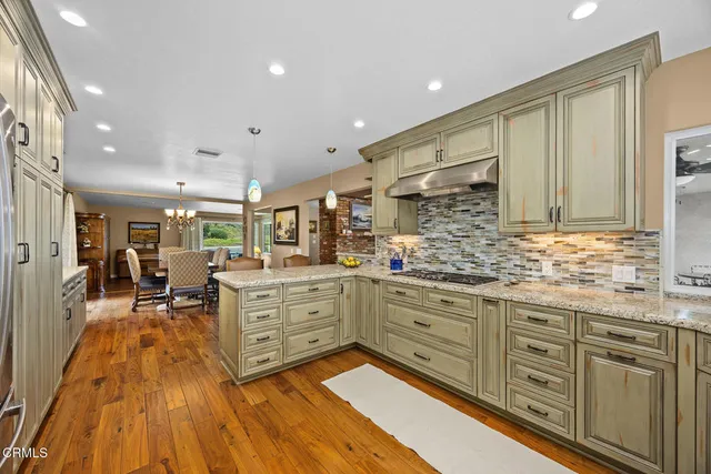 a kitchen with stainless steel appliances granite countertop a refrigerator and a stove top oven