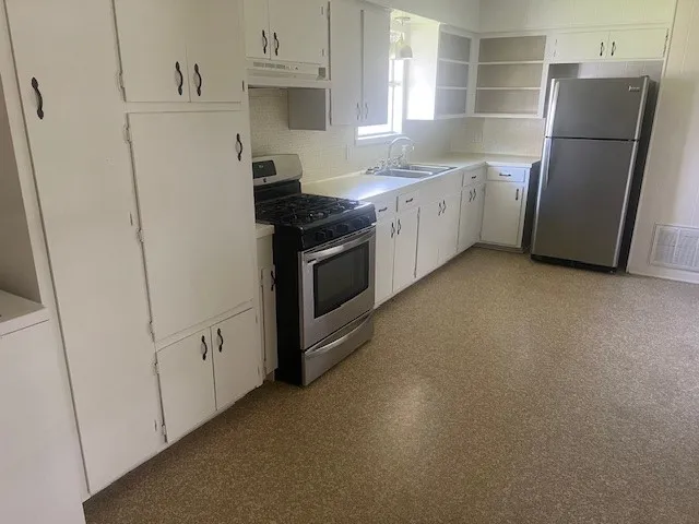 a kitchen with a refrigerator sink stove and cabinets
