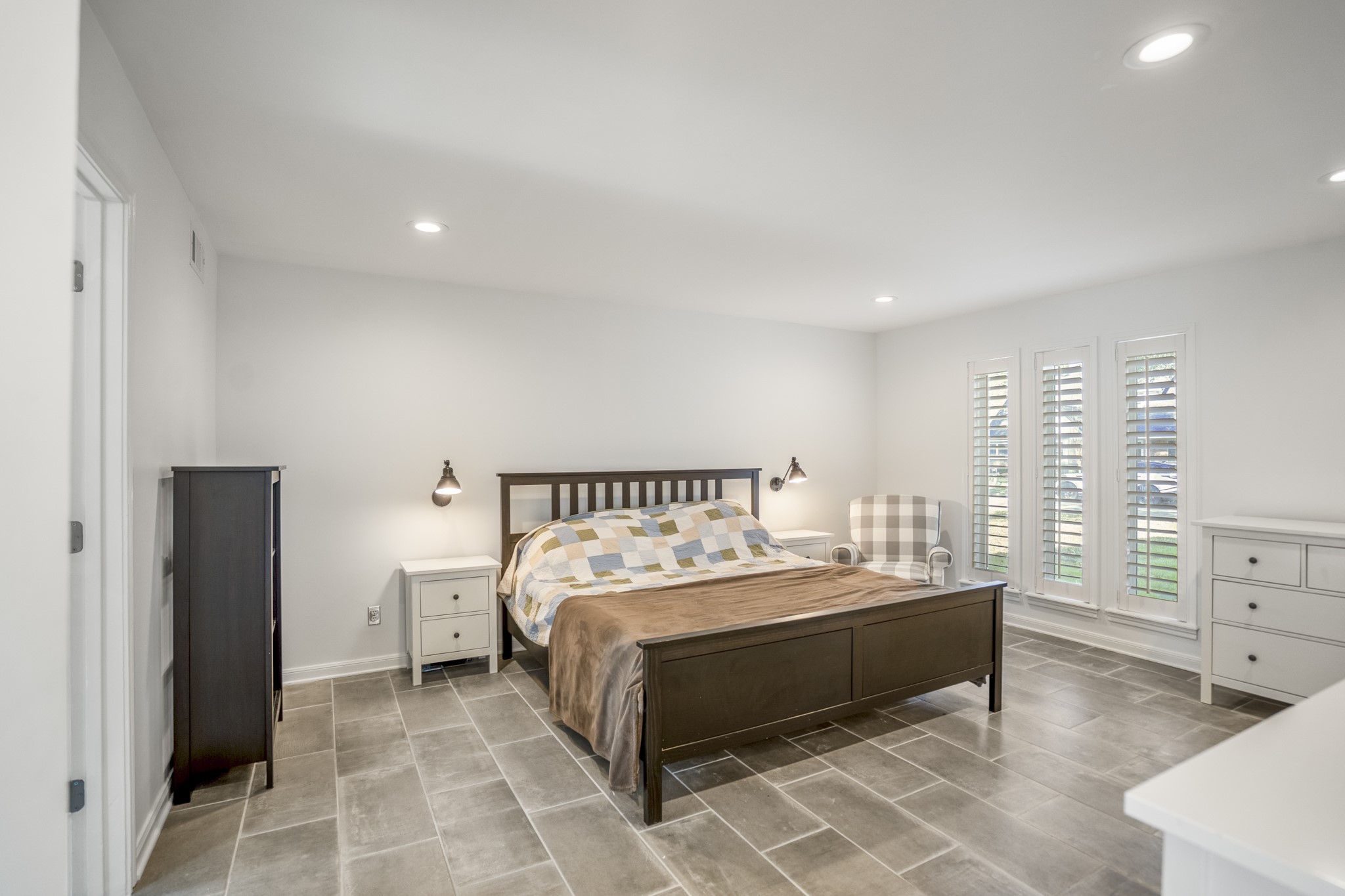 9507 Godstone Lane Spring, TX 77379 - Photo 19 of 42 Back to the front of the home, the master bedroom. Neutral ceramic flooring, plantation shutters, and wall sconces accent the room.