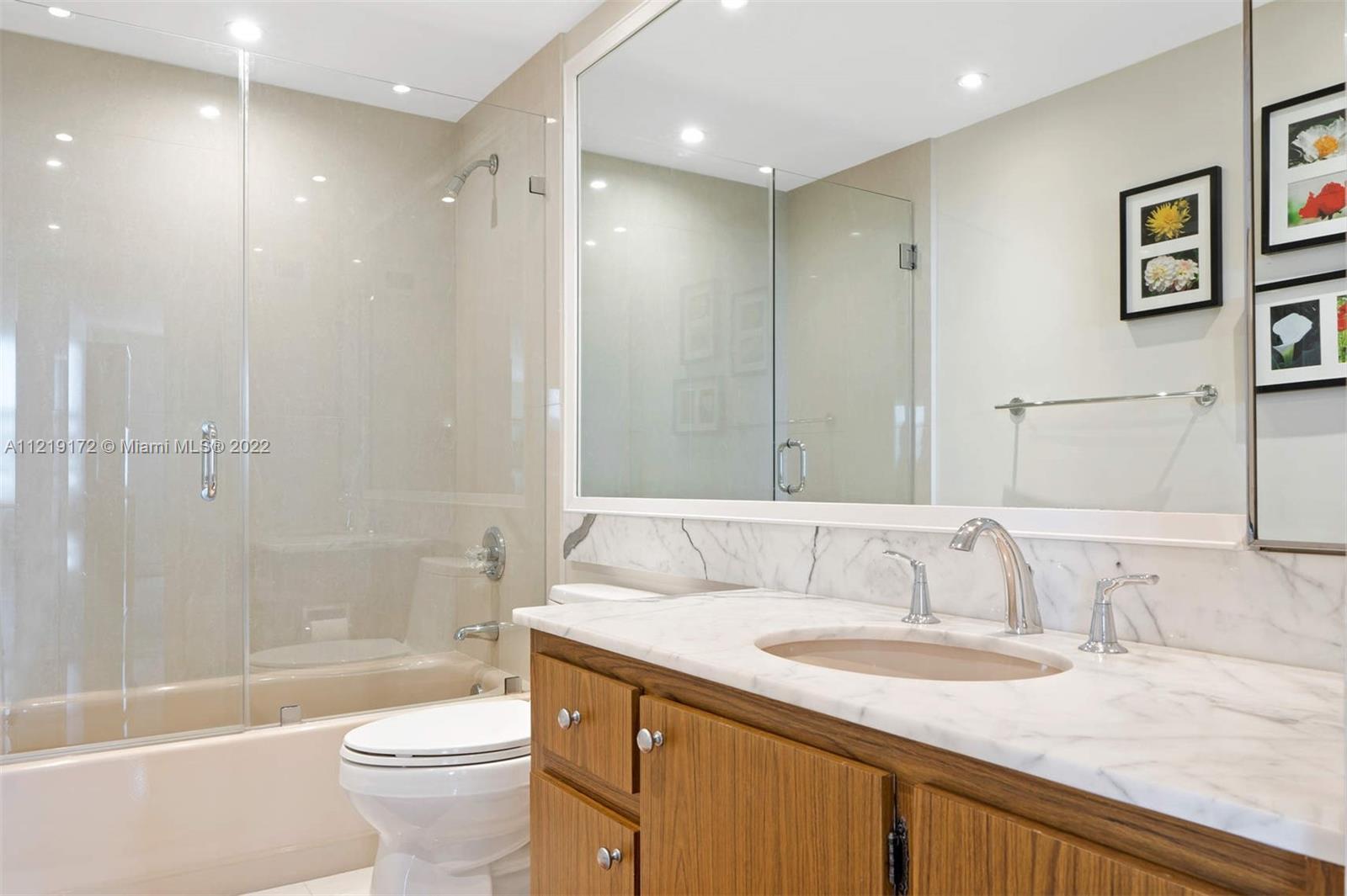 1121 Crandon Boulevard, Unit E801 Key Biscayne, FL 33149 - Photo 16 of 29 a bathroom with a granite countertop sink a toilet a mirror and bathtub