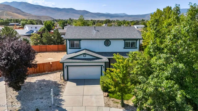 an aerial view of a house with a yard and mountain view in back