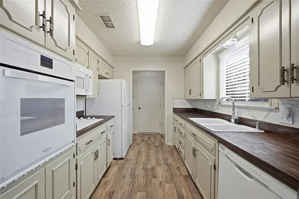 a kitchen with granite countertop a sink stove refrigerator and cabinets