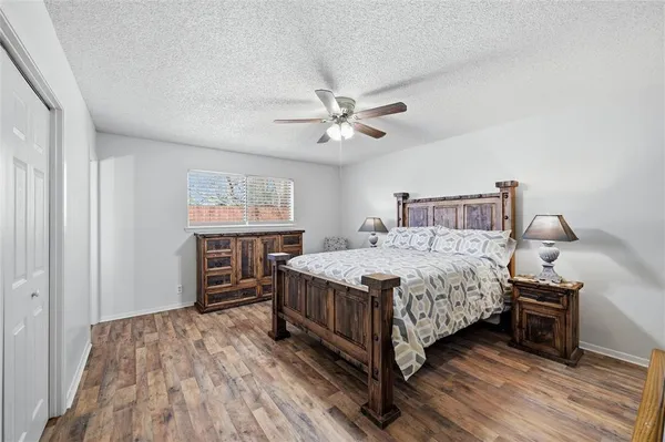 a bedroom with a bed and a ceiling fan with wooden floor