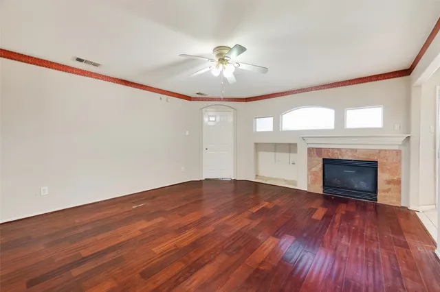 a view of an empty room with wooden floor fireplace and a window