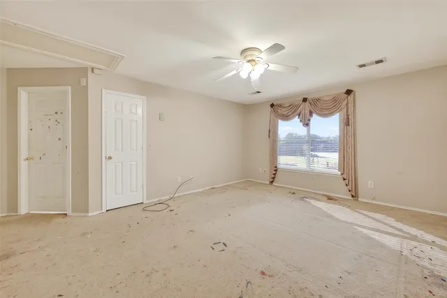 an empty room with a chandelier fan and windows