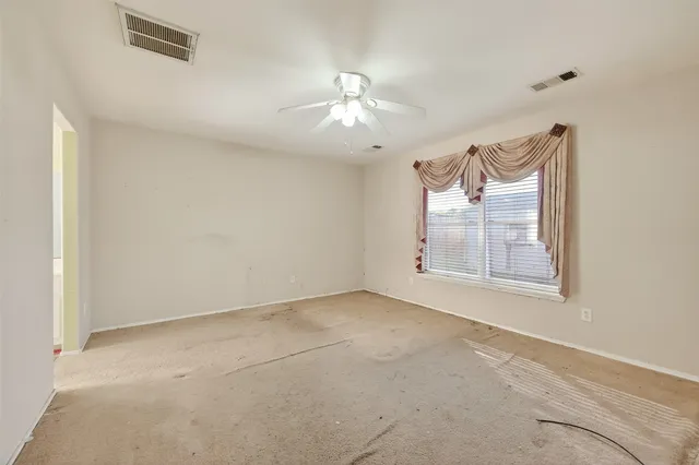 an empty room with windows and fan