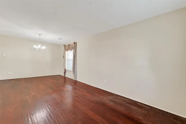 a view of an empty room with wooden floor and window