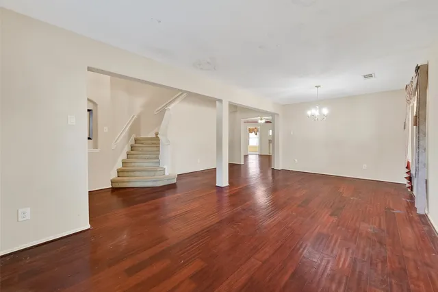 a view of an empty room with wooden floor and stairs