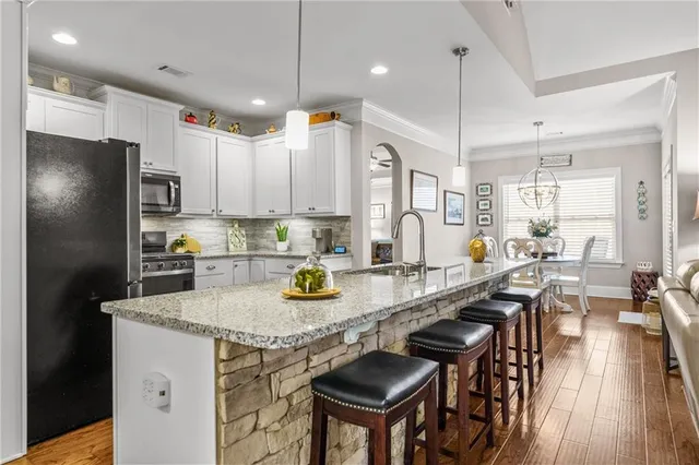 a kitchen with stainless steel appliances granite countertop a stove top oven a sink dishwasher a dining table and chairs with wooden floor