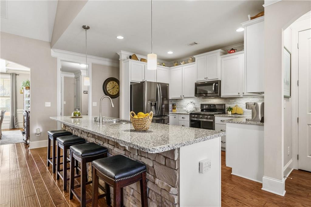 585 Hanover Drive Villa Rica, GA 30180 - Photo 17 of 72 a kitchen with stainless steel appliances granite countertop a stove top oven a sink dishwasher a dining table and chairs with wooden floor