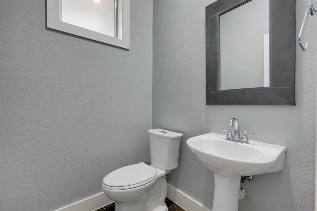 4830 Cedar Springs Road, Unit 30 Dallas, TX 75219 - Photo 14 of 32 Pedestal sink with chrome faucet, white toilet, and dark framed mirror