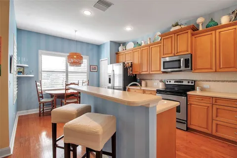 a kitchen with stainless steel appliances granite countertop a refrigerator stove and sink with wooden cabinets