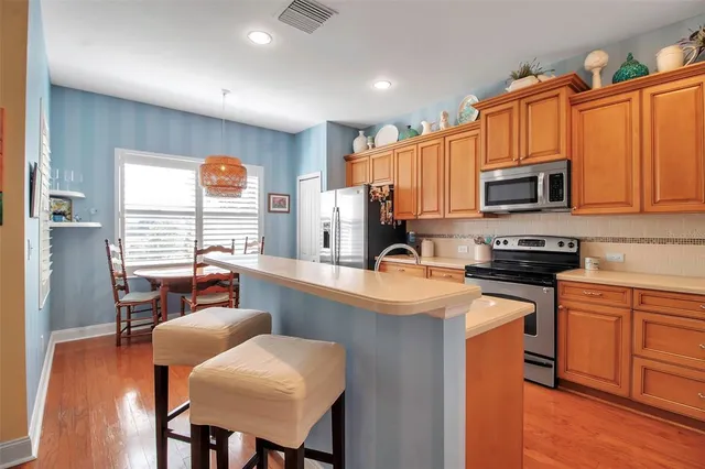 a kitchen with stainless steel appliances granite countertop a refrigerator stove and sink with wooden cabinets