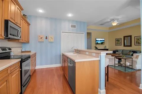 a kitchen with stainless steel appliances a table chairs microwave and sink
