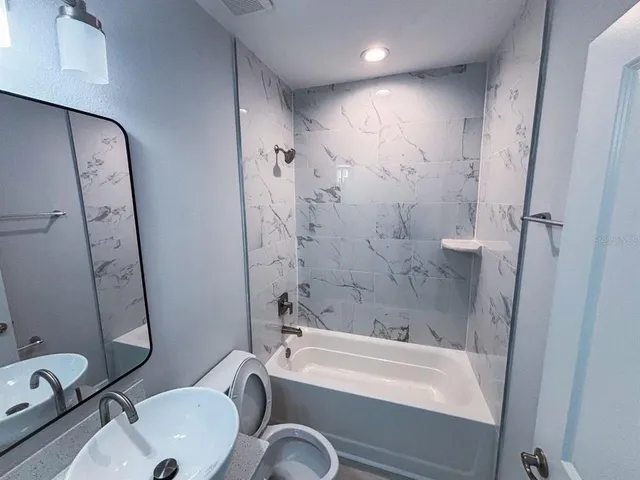 a bathroom with a sink a toilet a mirror and shower
