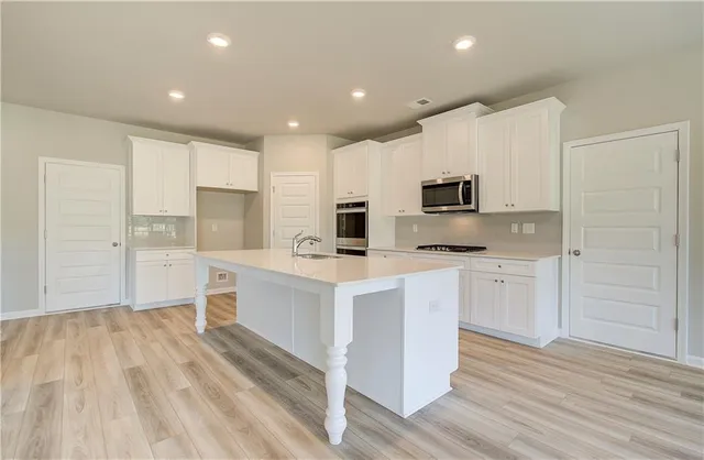a kitchen with white cabinets and stainless steel appliances