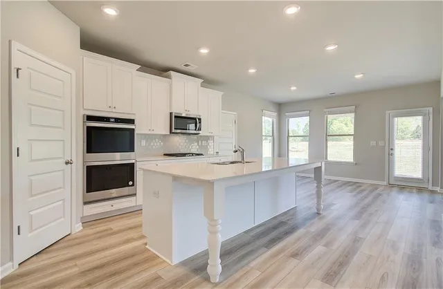 a large kitchen with kitchen island wooden floors and stainless steel appliances