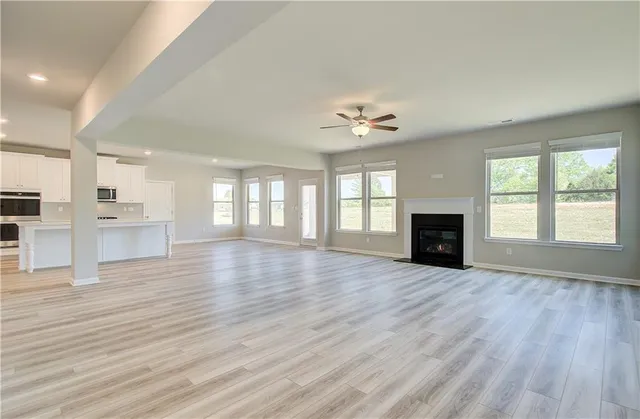 an empty room with wooden floor fireplace and windows