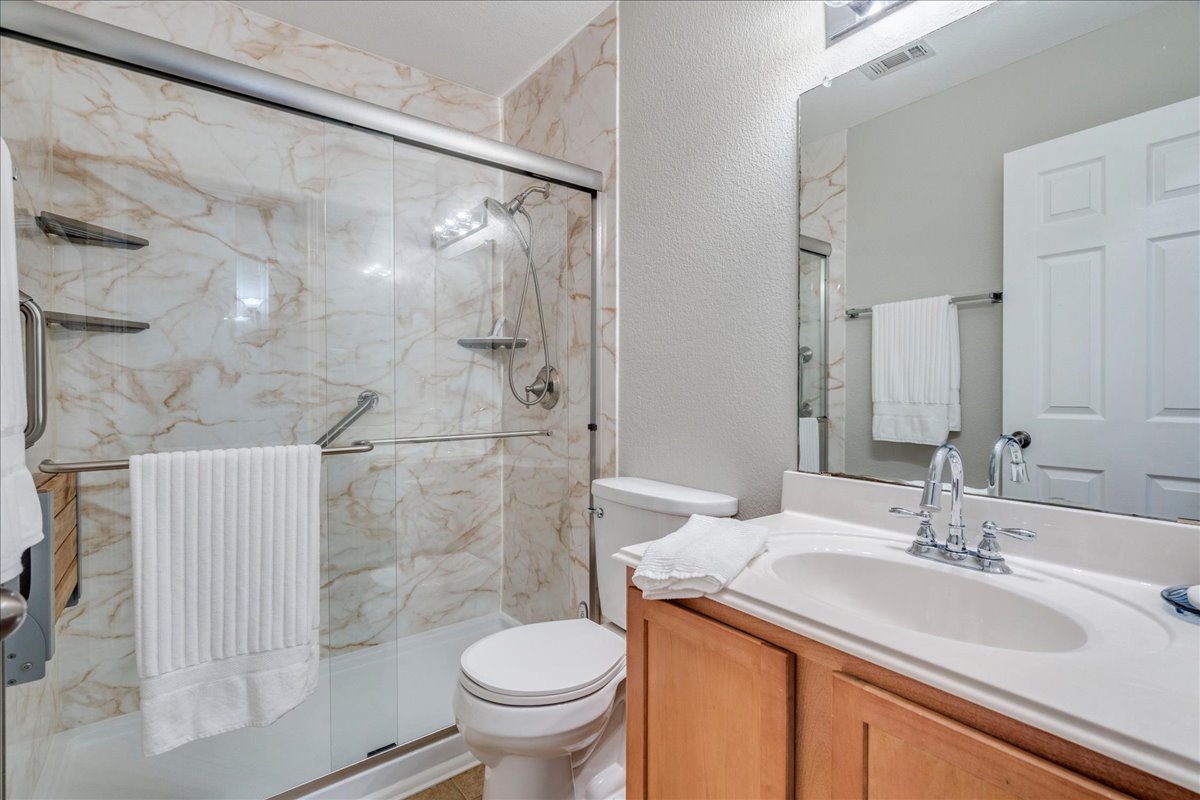 1151 Stone Rim Loop Buda, TX 78610 - Photo 22 of 36 Secondary bathroom features a walk-in shower with glass doors and marble-patterned wall panels