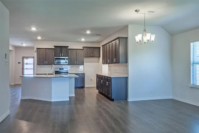 a large kitchen with hardwood floor and a chandelier