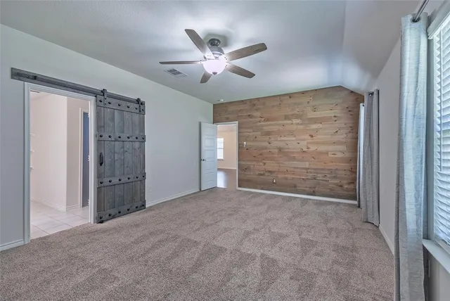 a view of an empty room with cabinet and a ceiling fan