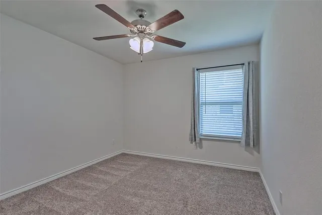 an empty room with a window and a fan