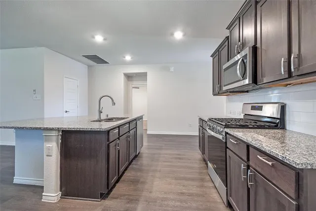 a kitchen with stainless steel appliances granite countertop a stove top oven a sink and dishwasher