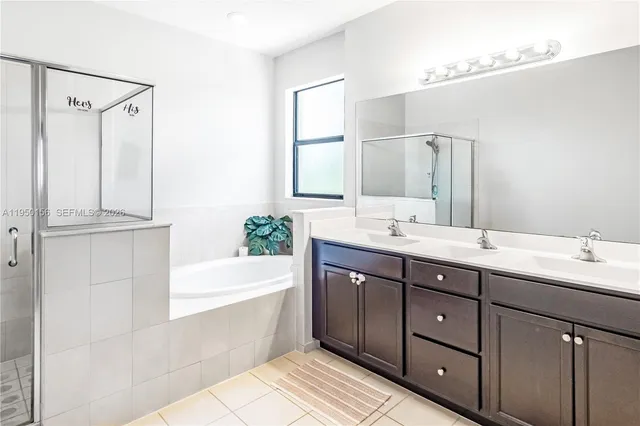 a bathroom with a tub a sink double vanity and shower