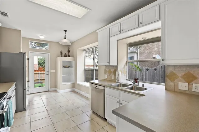 a kitchen with stainless steel appliances a refrigerator a sink a stove and white cabinets