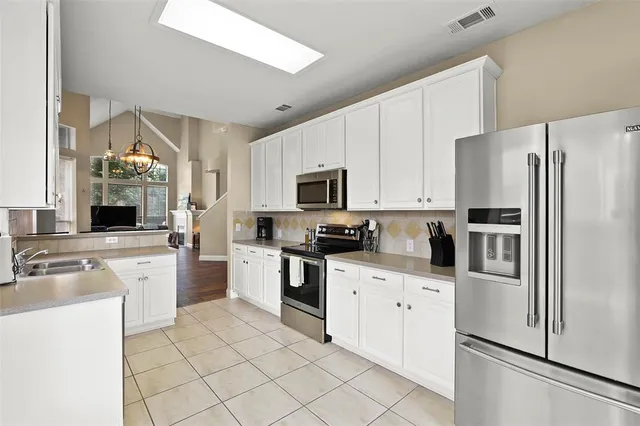 a kitchen with white cabinets and stainless steel appliances