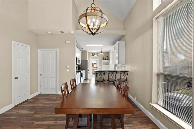 a dining room with wooden floor a chandelier a wooden table and chairs