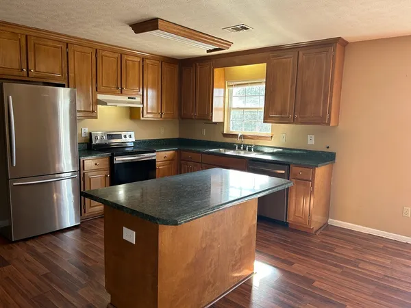 a kitchen with kitchen island granite countertop a sink stove and refrigerator