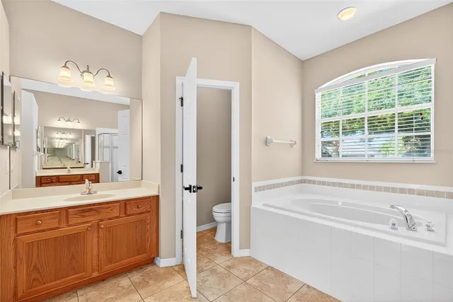 a view of an empty room with window and chandelier fan