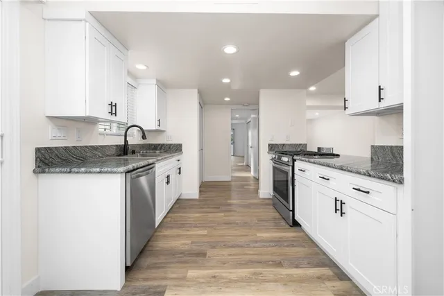 a large kitchen with stainless steel appliances granite countertop a lot of counter space and wooden floors