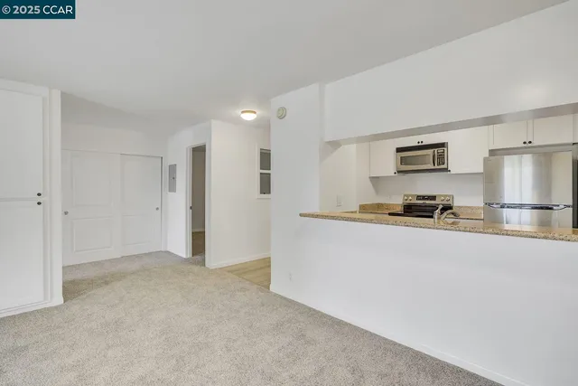 a view of kitchen with stainless steel appliances granite countertop white cabinets and refrigerator