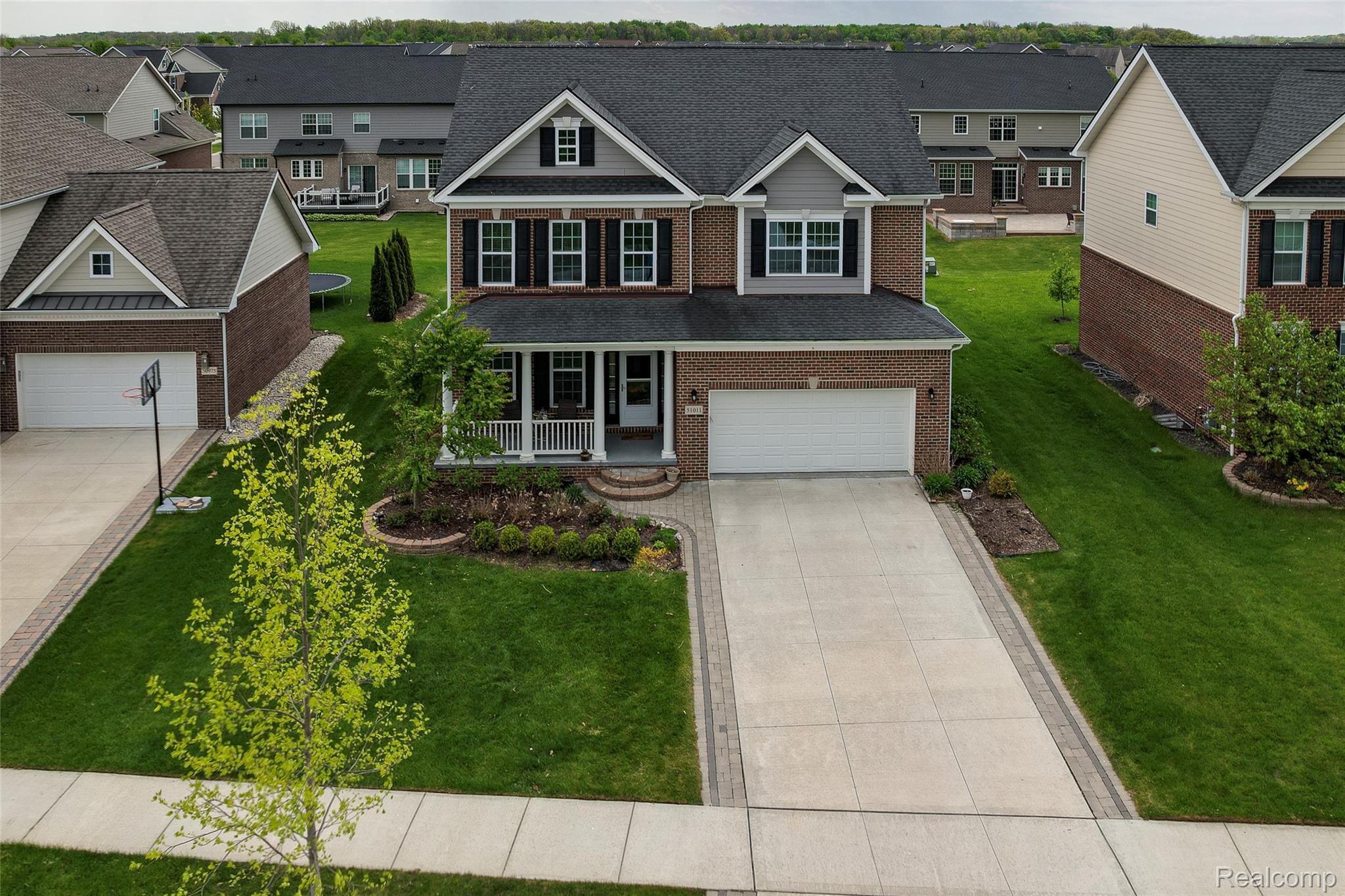 51011 Rockingham Drive Canton, MI 48188 - Photo 61 of 74 Traditional-style home featuring a porch, concrete driveway, a front yard, an attached garage, and brick siding