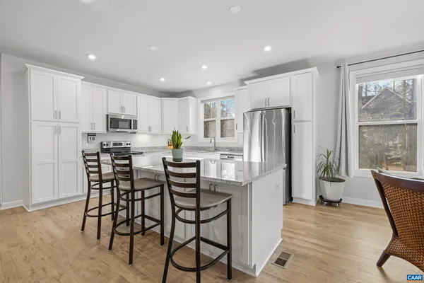 a kitchen with granite countertop a refrigerator a sink a stove a microwave and island with wooden floor